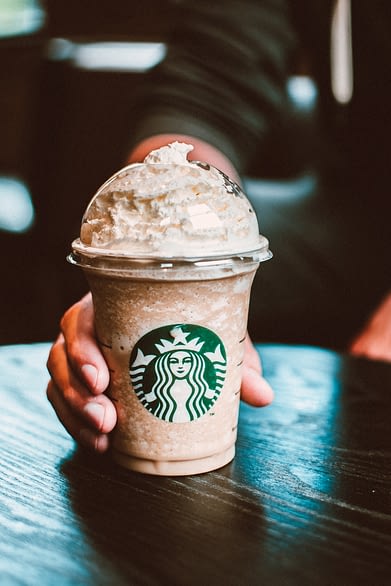 Man holding a Starbucks coffee at a cafe on a table